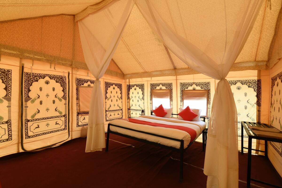 A tent-style room with a bed, curtains, and patterned walls.