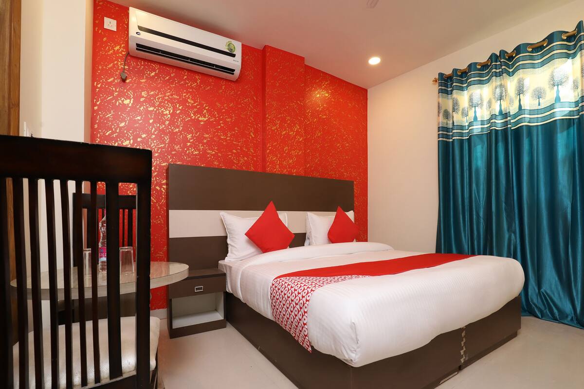 Une chambre d’hôtel avec un lit, une table de chevet, une chaise et un mur rouge à texture.