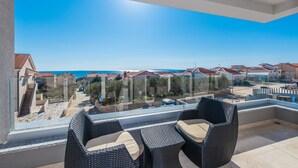 A balcony with wicker furniture and a clear view of the sea and neighboring buildings. - Apartments with Pool Villa Zora (Novalja)