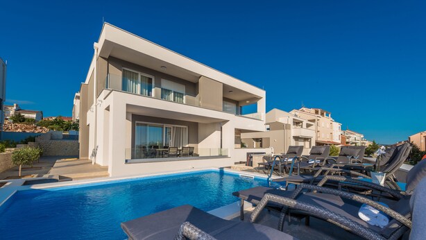 A modern hotel with a swimming pool, lounge chairs, and a clear blue sky. - Apartments with Pool Villa Zora (Novalja)