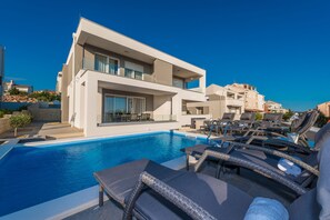 A modern hotel with a swimming pool, lounge chairs, and a clear blue sky. - Apartments with Pool Villa Zora (Novalja)