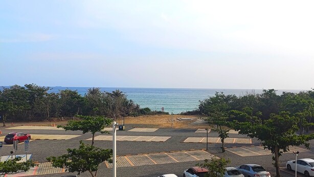 A parking lot with cars and trees, overlooking a body of water. - Tz Shin Resort Hostel (Hengchun)
