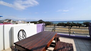 A wooden table and bench on a balcony with a view of the beach and ocean. - Tz Shin Resort Hostel (Hengchun)