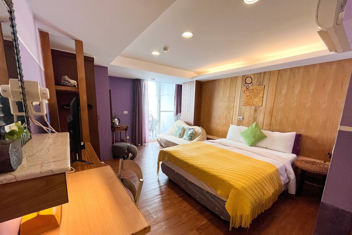 Una habitación de hotel con cama, mesita de noche, silla y escritorio con ordenador.