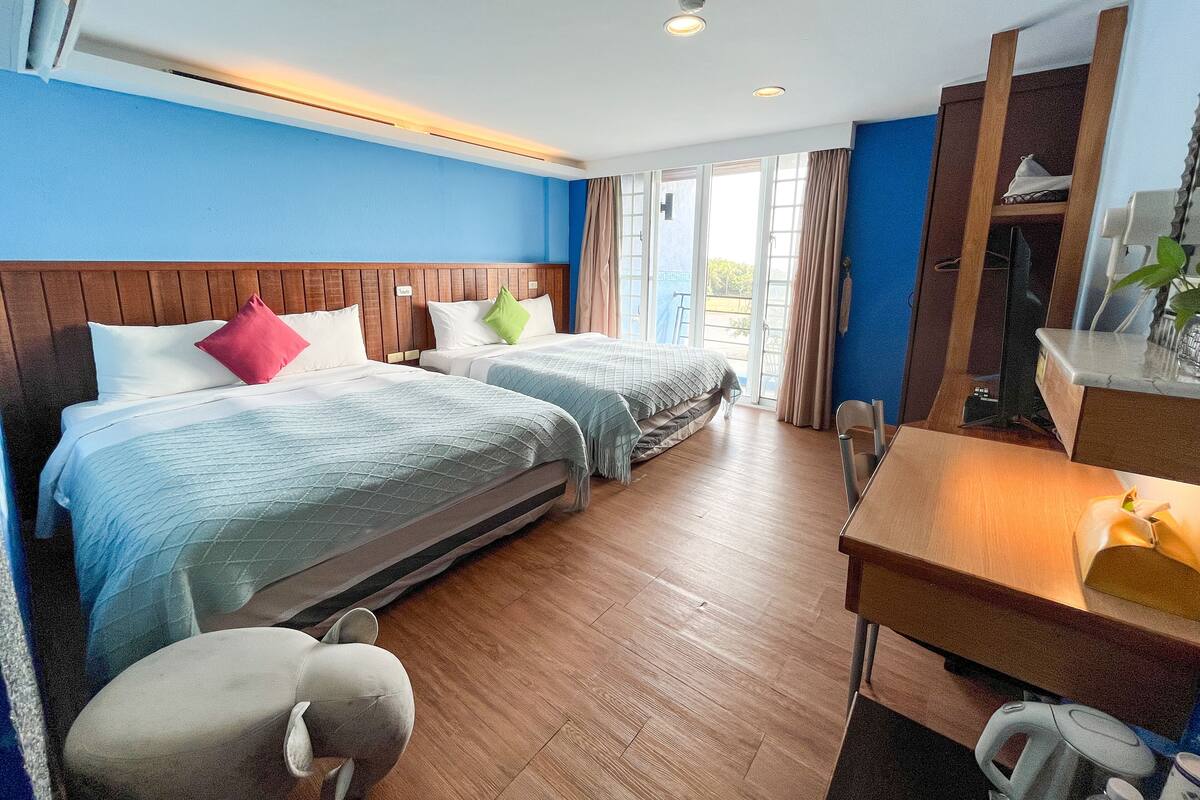 Una habitación de hotel con dos camas, un cabecero de madera, un escritorio y una silla.