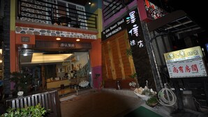A hotel entrance with a stone facade, a wooden balcony, and a signboard with contact information. - Tz Shin Resort Hostel (Hengchun)