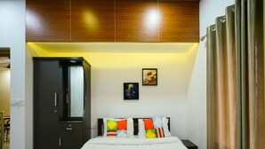 A bedroom with a bed, a wardrobe, a nightstand, and a wall-mounted picture. - OYO 16630 Home Cocoa Tree Residency (Devikolam)
