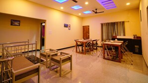 A spacious room with a staircase, a dining area with tables and chairs, ceiling fans, and recessed lighting. - OYO 16630 Home Cocoa Tree Residency (Devikolam)