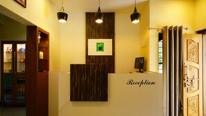 A reception desk with a 'Reception' sign, a framed certificate, and a computer monitor. - OYO 16630 Home Cocoa Tree Residency (Devikolam)