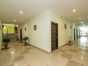 Stunning hallway with a checkered tile floor, potted plants, and a door leading to a bright, airy space.