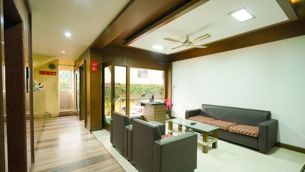 A hotel lobby with a reception desk, a sofa, and a small table. - OYO 3633 Nanda Inn (Kanayannur)