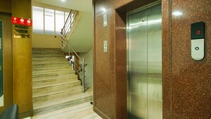 A hotel lobby with a marble staircase, an elevator, and a sign indicating a web zone. - OYO 3633 Nanda Inn (Kanayannur)
