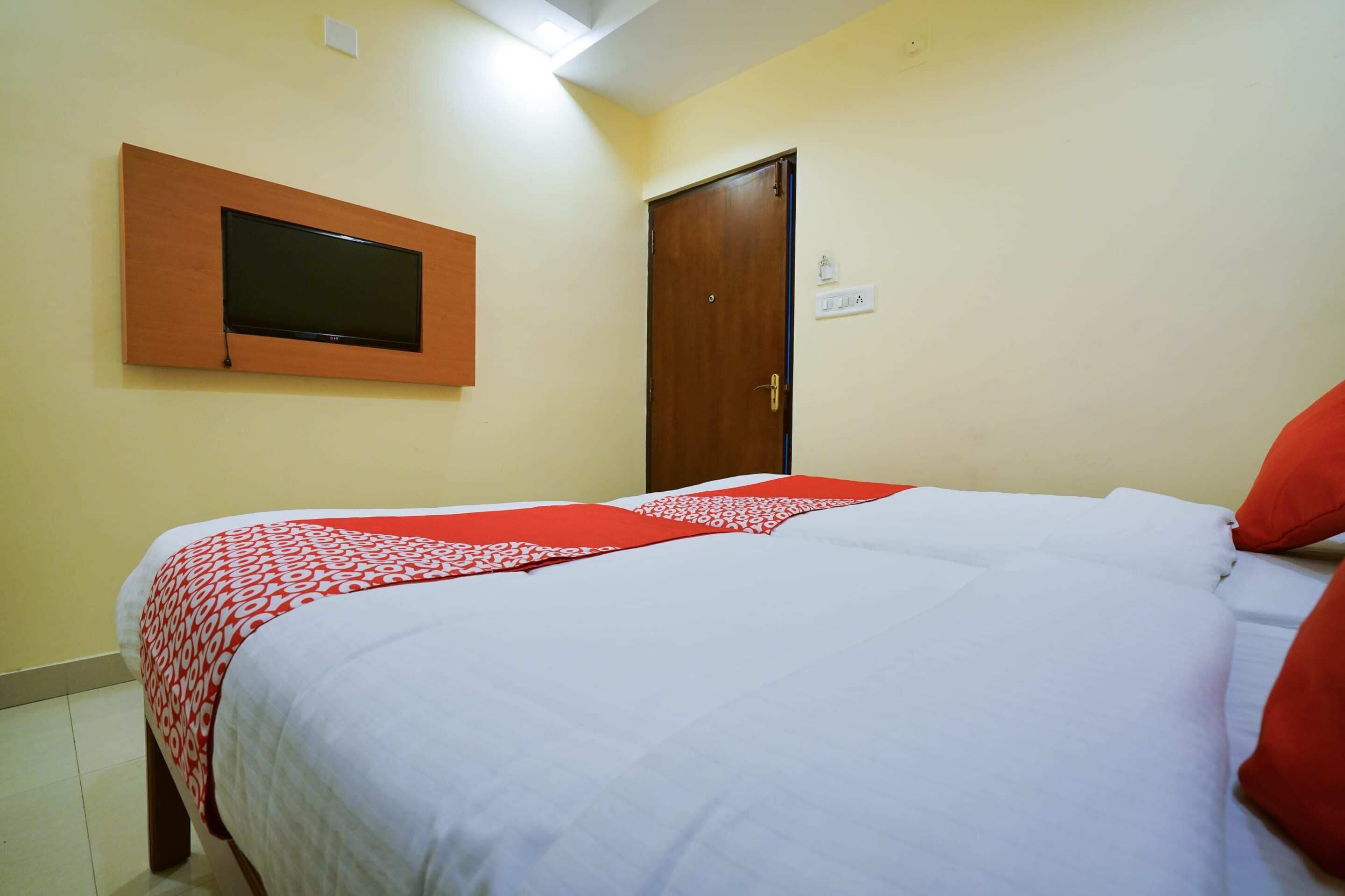 A hotel room with a bed, a television mounted on the wall, and a door.