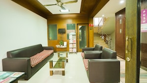 A lobby with a reception desk, two sofas, a coffee table, a television, a staircase, and a 'PUSH' sign. - OYO 3633 Nanda Inn (Kanayannur)