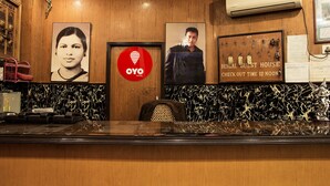 Een hotel receptie met een houten balie, ingelijste foto's, een rood OYO logo en een bordje voor Bengal Guest House.