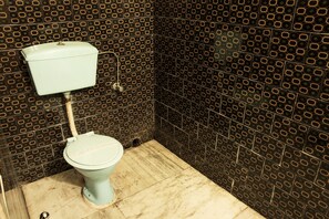 A toilet in a bathroom with a patterned tile wall.