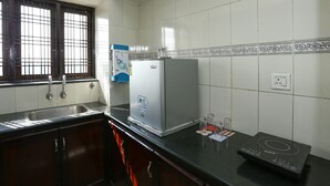 A kitchen with a refrigerator, a water dispenser, a sink, and a stove. - OYO 23654 Home Cozy 2BHK Aluva Metro Station (Aluva)