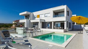 A modern two-story house with a swimming pool, outdoor seating, and a yellow umbrella. - Apartments Villa Dalia (Novalja)