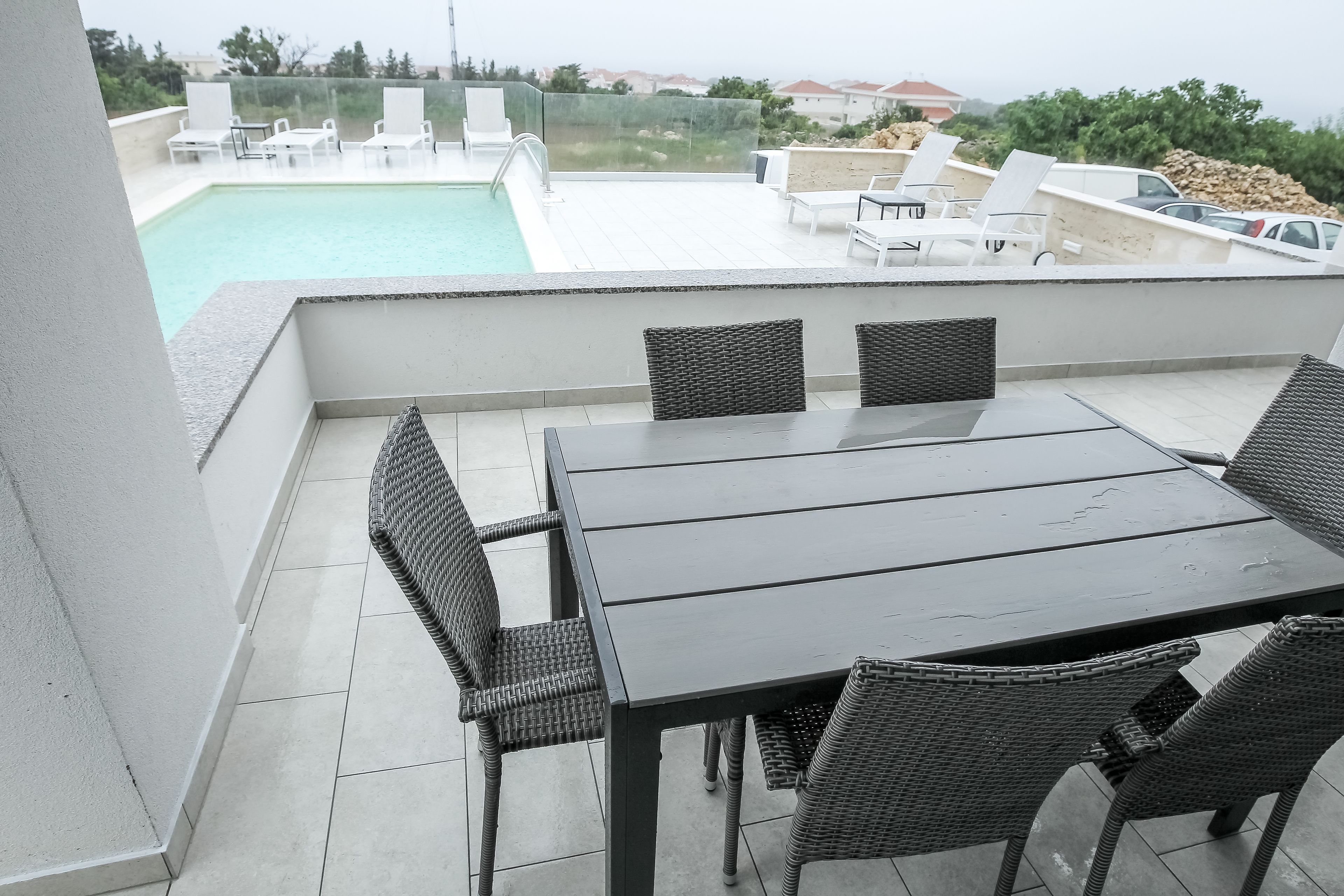 A rooftop terrace with a pool, outdoor seating, and a view of the surrounding area.