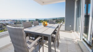 A balcony with a table and wicker chairs, overlooking a scenic view. - Apartments Villa Dalia (Novalja)