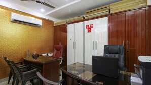 A conference room with a wooden desk, chairs, a large mirror, and a wardrobe with a 'No Smoking' sign. - OYO 7571 Madhapur (Hyderabad)