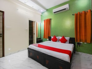 A hotel room with a bed, green walls, and orange curtains.