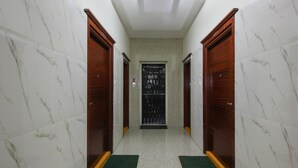 A hallway with marble walls and wooden doors, leading to a black gate. - OYO 7571 Madhapur (Hyderabad)
