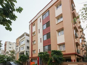 Un edificio residencial de varios pisos con fachada color beige, detalles en rojo y múltiples balcones.