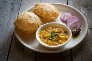 A plate with two fried breads, a bowl of dal, and sliced onions. - OYO 17200 Flagship Hotel Neelkamal (Mumbai)