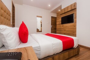 Ein modernes Schlafzimmer mit einem Holzkopfende, einem großen Bett mit weißer und roter Bettwäsche, einem flachbildfernseher an der Wand und einem Nachttisch aus Holz.