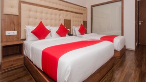 A hotel room with a large bed, two red pillows, a wooden headboard, and a large window. - OYO 22039 Hotel Bkc Grand (Mumbai)
