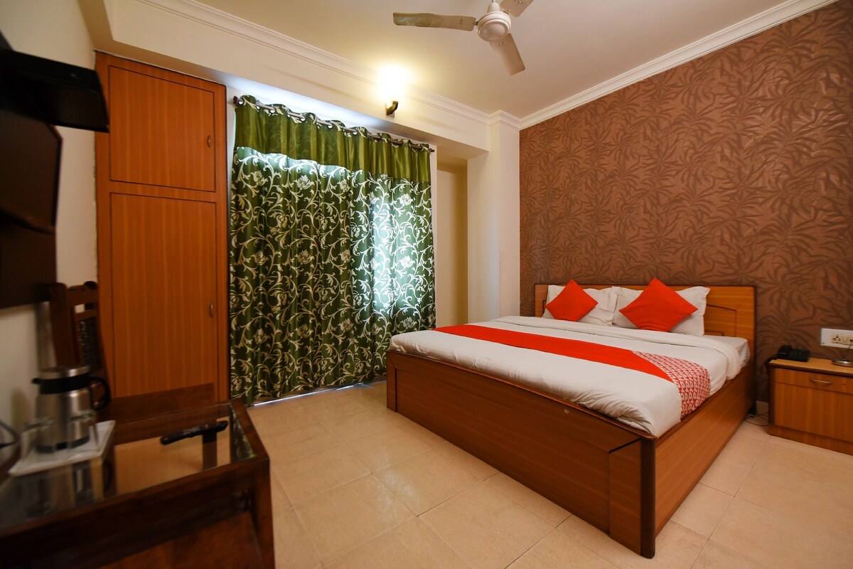 A neatly arranged bedroom with a bed, a wooden wardrobe, a nightstand, and a ceiling fan.