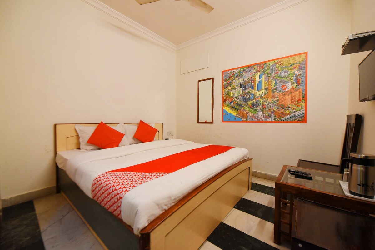 A hotel room with a bed, a coffee maker, and a painting on the wall.