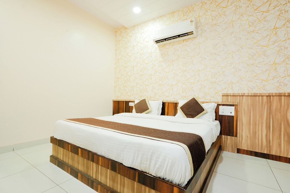 A neatly made bed with a wooden headboard and a patterned wall.