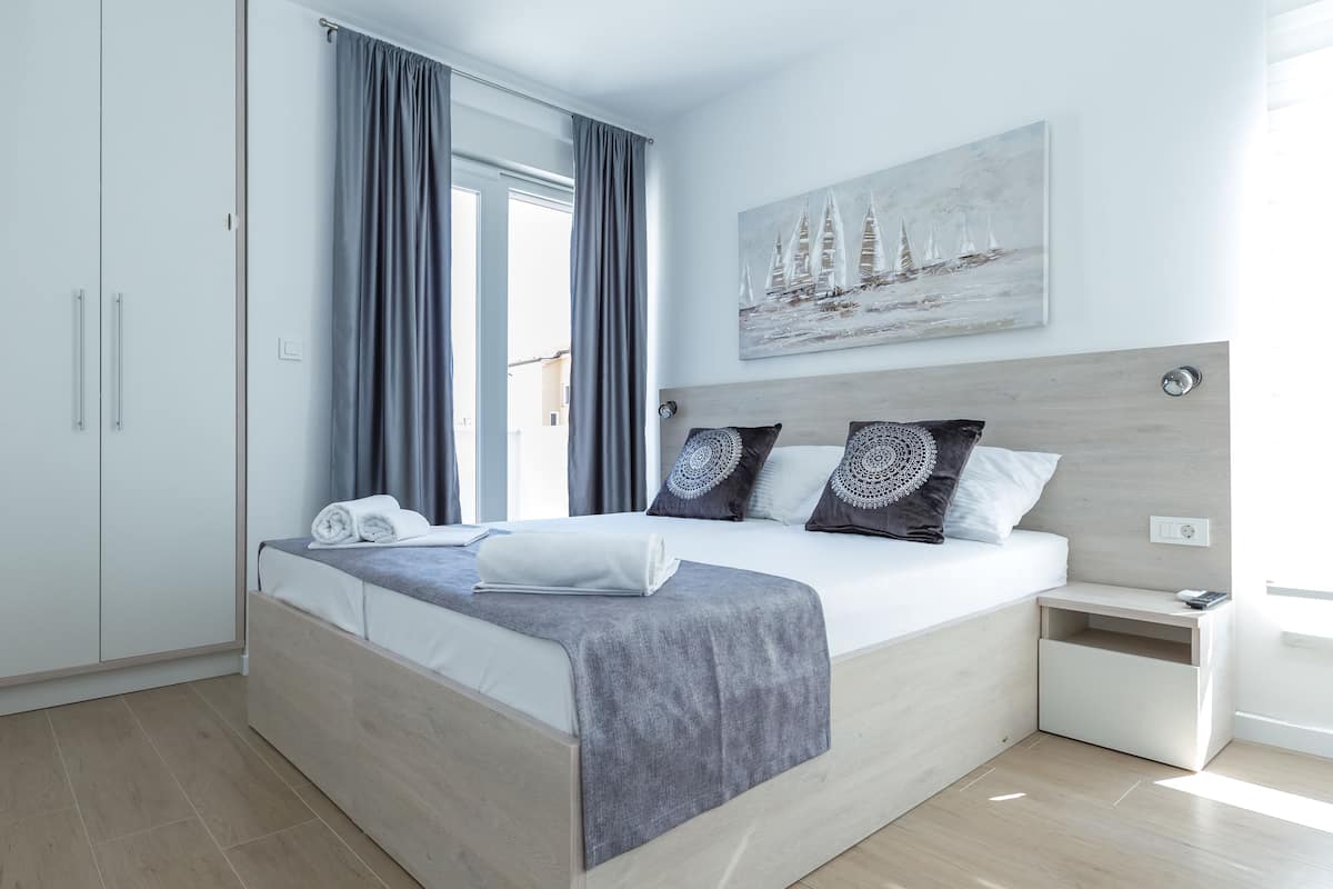 A modern bedroom with a large bed, a bedside table, and a painting on the wall.