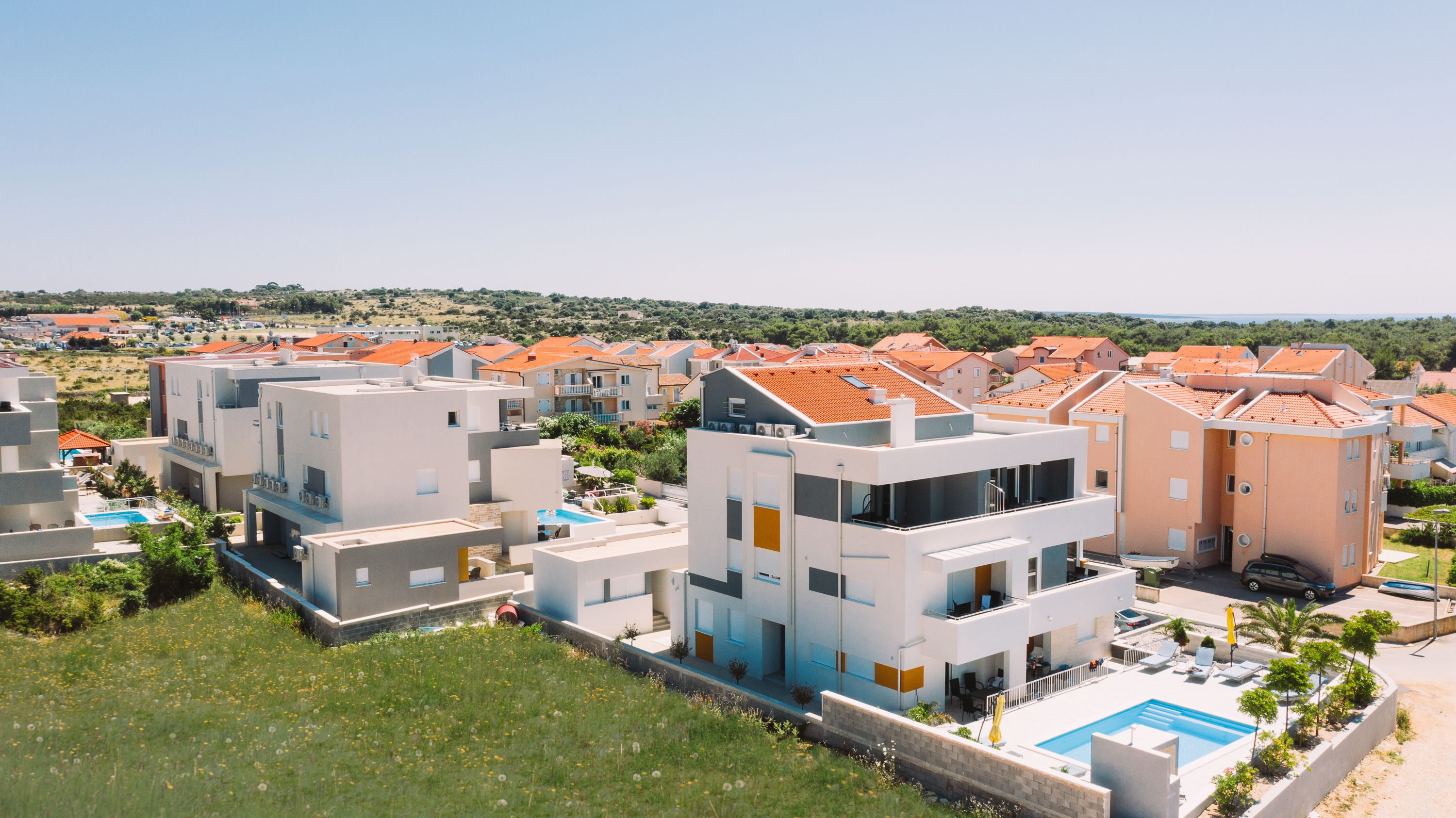 A modern residential area with multi-story buildings, a swimming pool, and a landscaped garden.