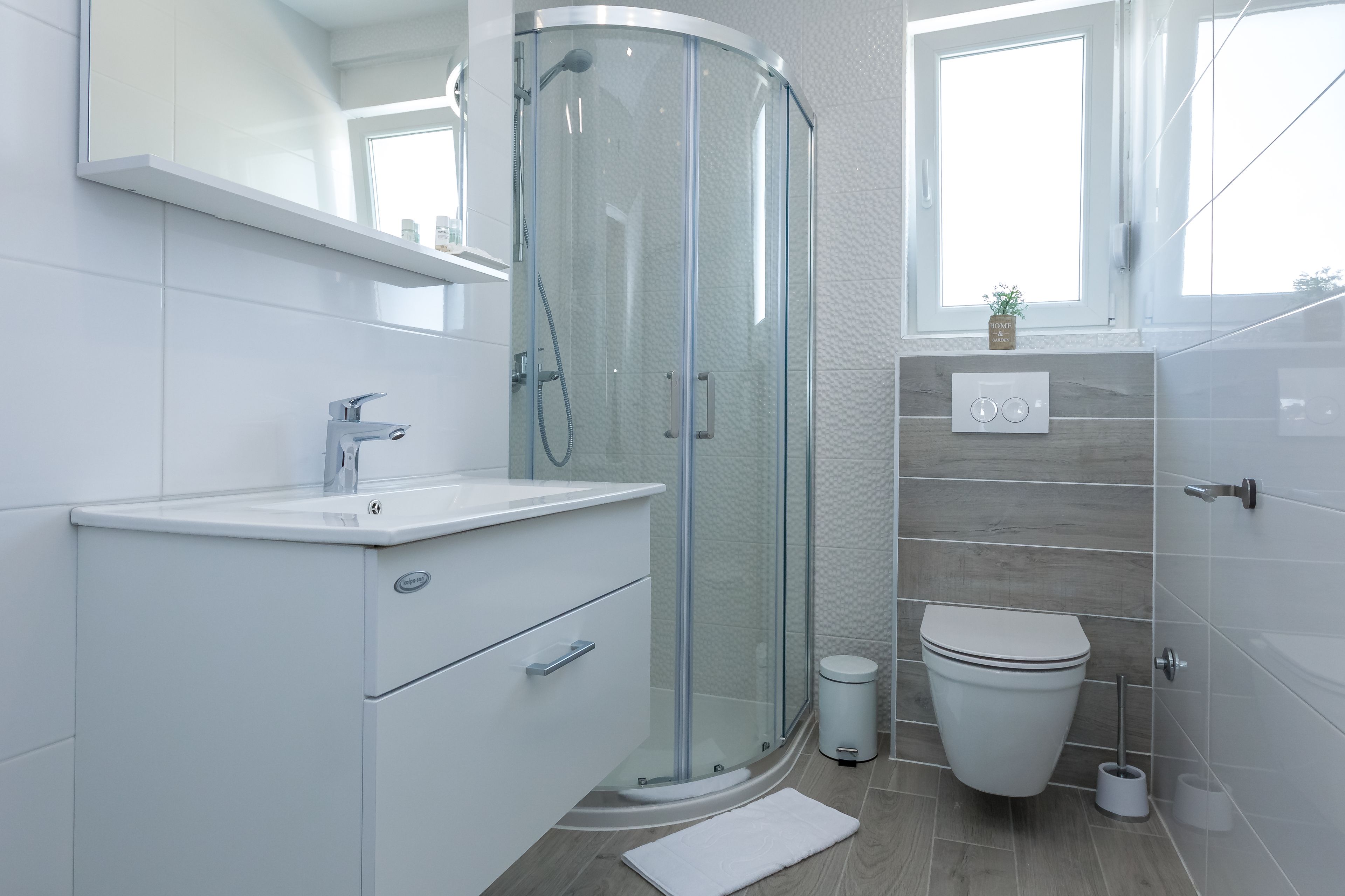 A modern bathroom with a glass shower enclosure, a white toilet, and a vanity with a sink.