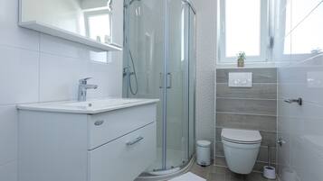 A modern bathroom with a glass shower enclosure, a white toilet, and a vanity with a sink.