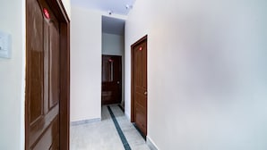A hallway with wooden doors and a tiled floor. - CAPITAL O 15141 Townvilla Guest House (Hyderabad)