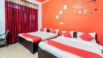 A hotel room with two beds, red and white bedding, a red curtain, and a wall with framed pictures.