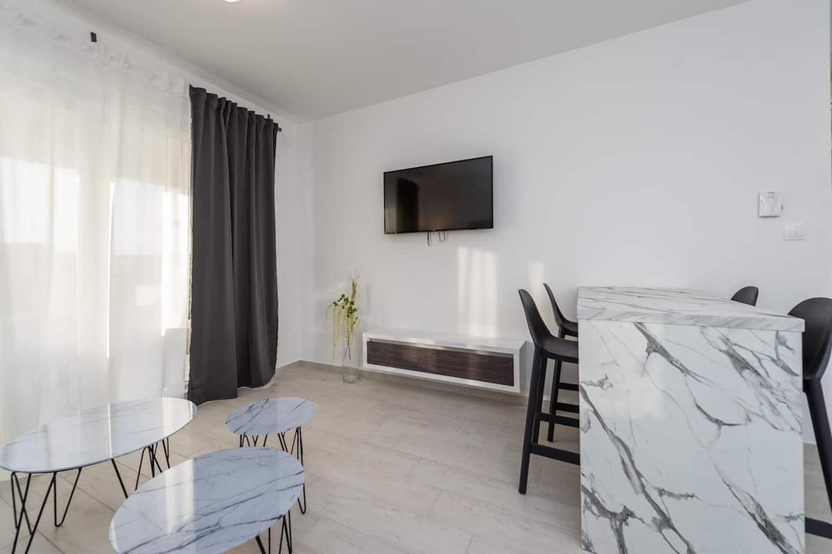 A modern room with a TV mounted on the wall, a dining table with chairs, and a bench.