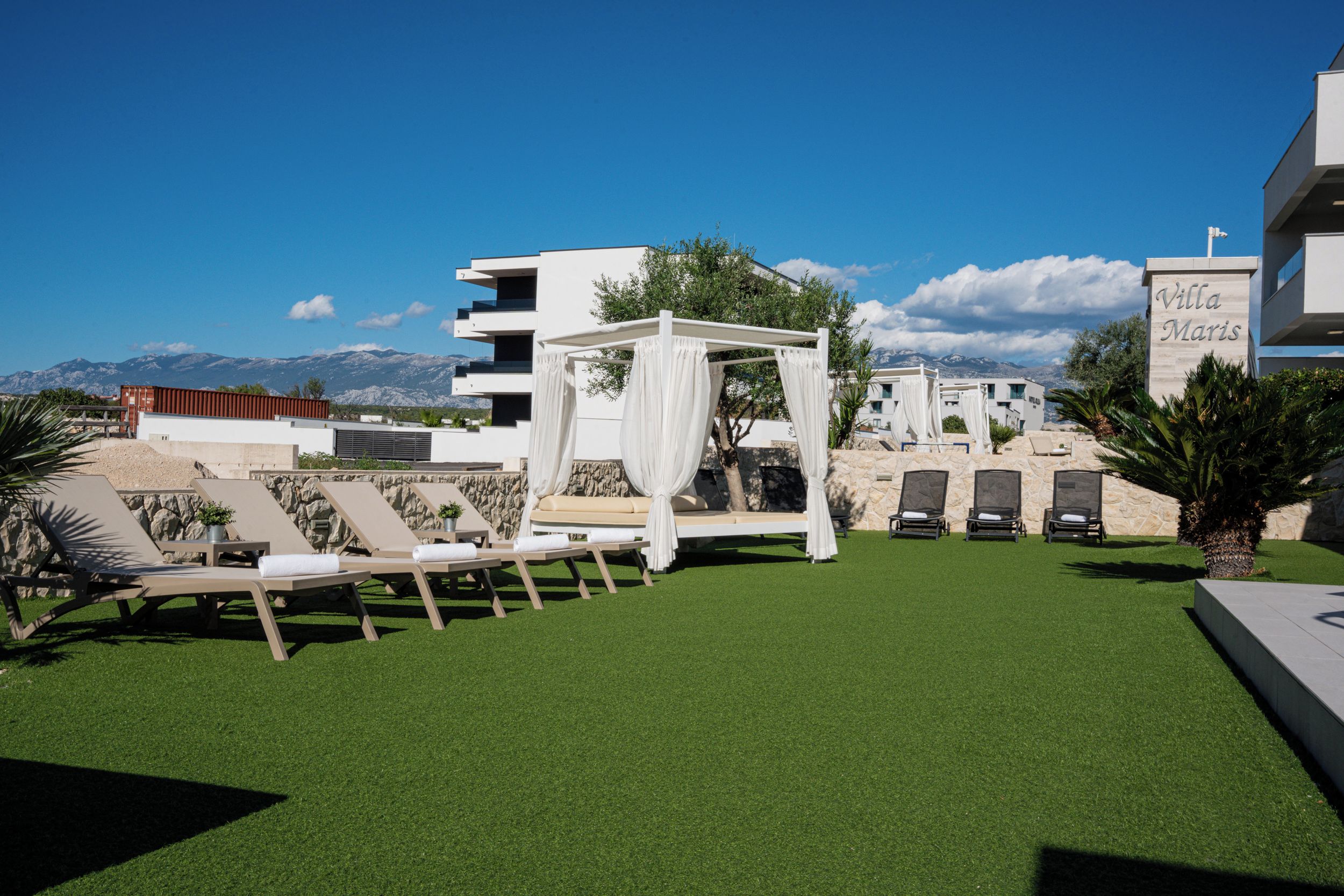 A resort with a pool area, outdoor seating, and a view of mountains.