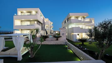 A modern multi-story hotel with a pool area, outdoor seating, and a well-maintained lawn.