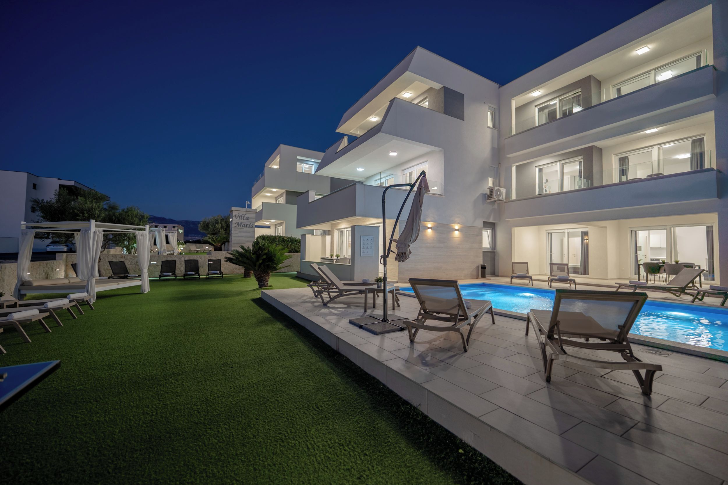 A modern multi-story building with a swimming pool and outdoor seating.