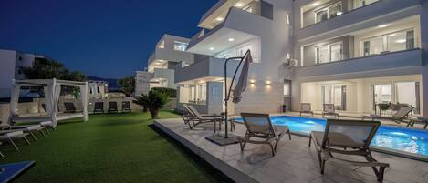 A modern multi-story building with a swimming pool and outdoor seating.