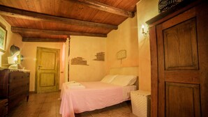 Un dormitorio acogedor con techo de madera, una cama con colcha rosa, un aparador y una puerta.
