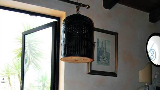 Una habitación con un amplio ventanal corredero que da a un espacio exterior, una lámpara colgante, un aparador de madera y un reloj fijado a la pared.