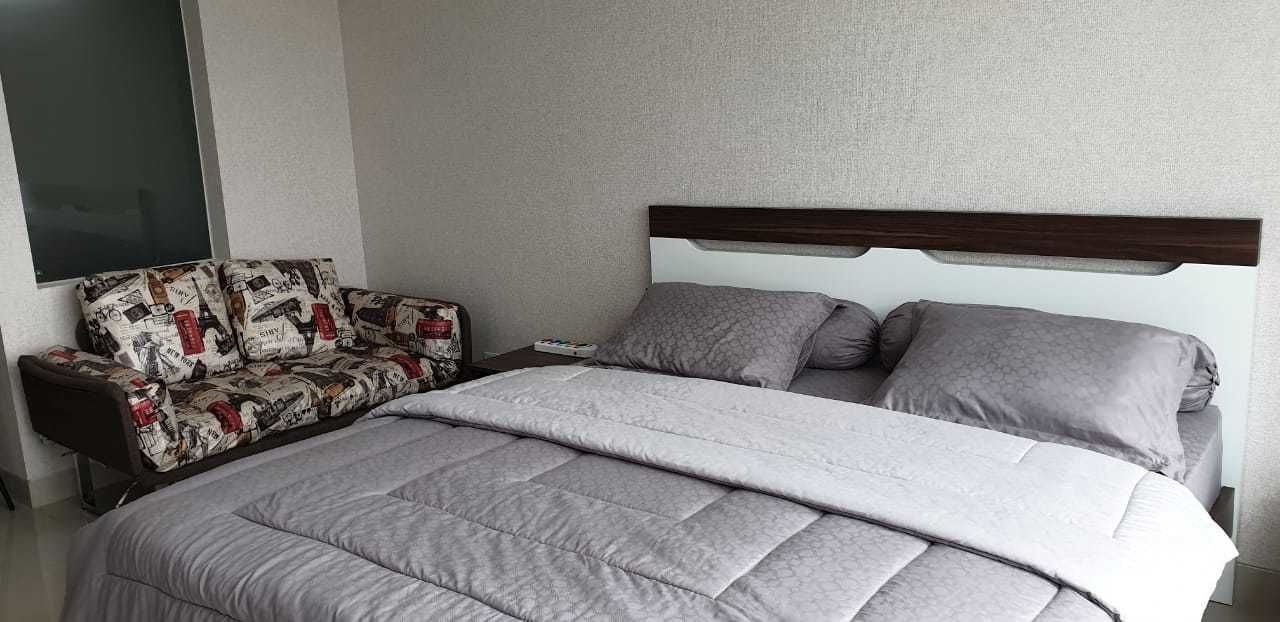 Un dormitorio con una cama, una mesita de noche y un sofá.