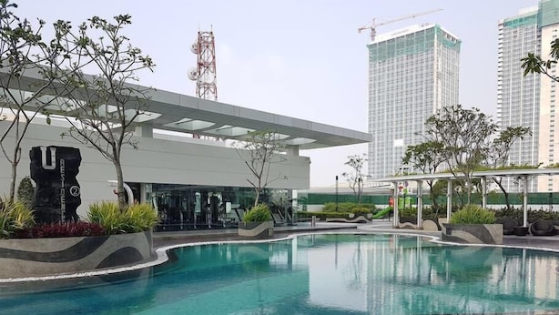 A swimming pool with a modern building and high-rise buildings in the background.