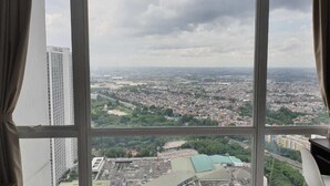 A room with a large window offering a cityscape view.